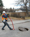 Utility worker removing manhole cover using Camlift lifter.